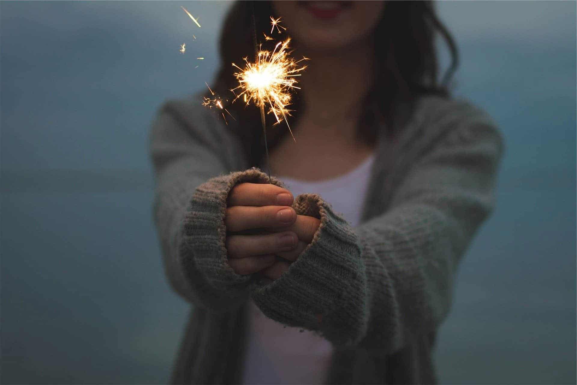 Woman holding a sparkler to celebrate a positive mindset in the new year
