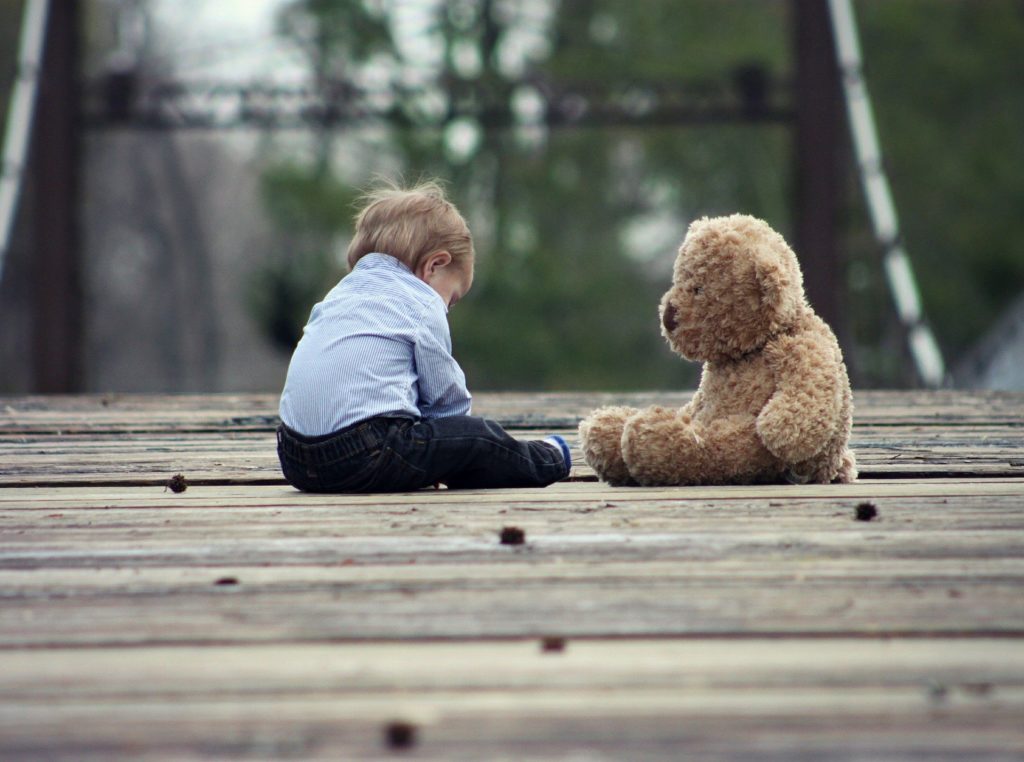 Baby and teddy bear sad on a bridge